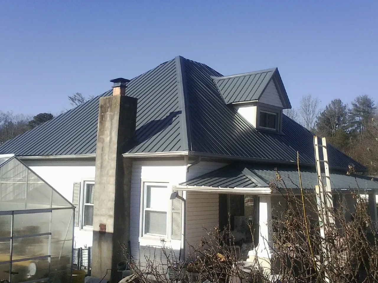 Dark blue standing seam metal roof on a white farmhouse with dormer — Slate & Tile Roof Repair by Roofing Brothers in Shaniko