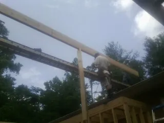 Carpenter setting a ridge beam over a new addition frame — Ice Dam Removal by Roofing Brothers in Shaniko