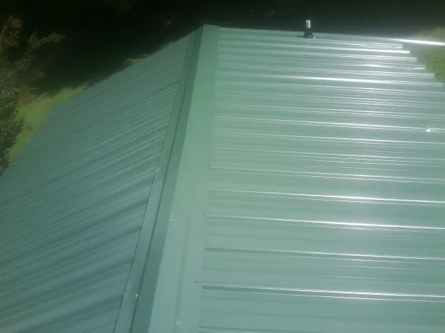 New green metal panels meeting at the ridge of a roof — Flat Roof Repair work by our crew in Shaniko