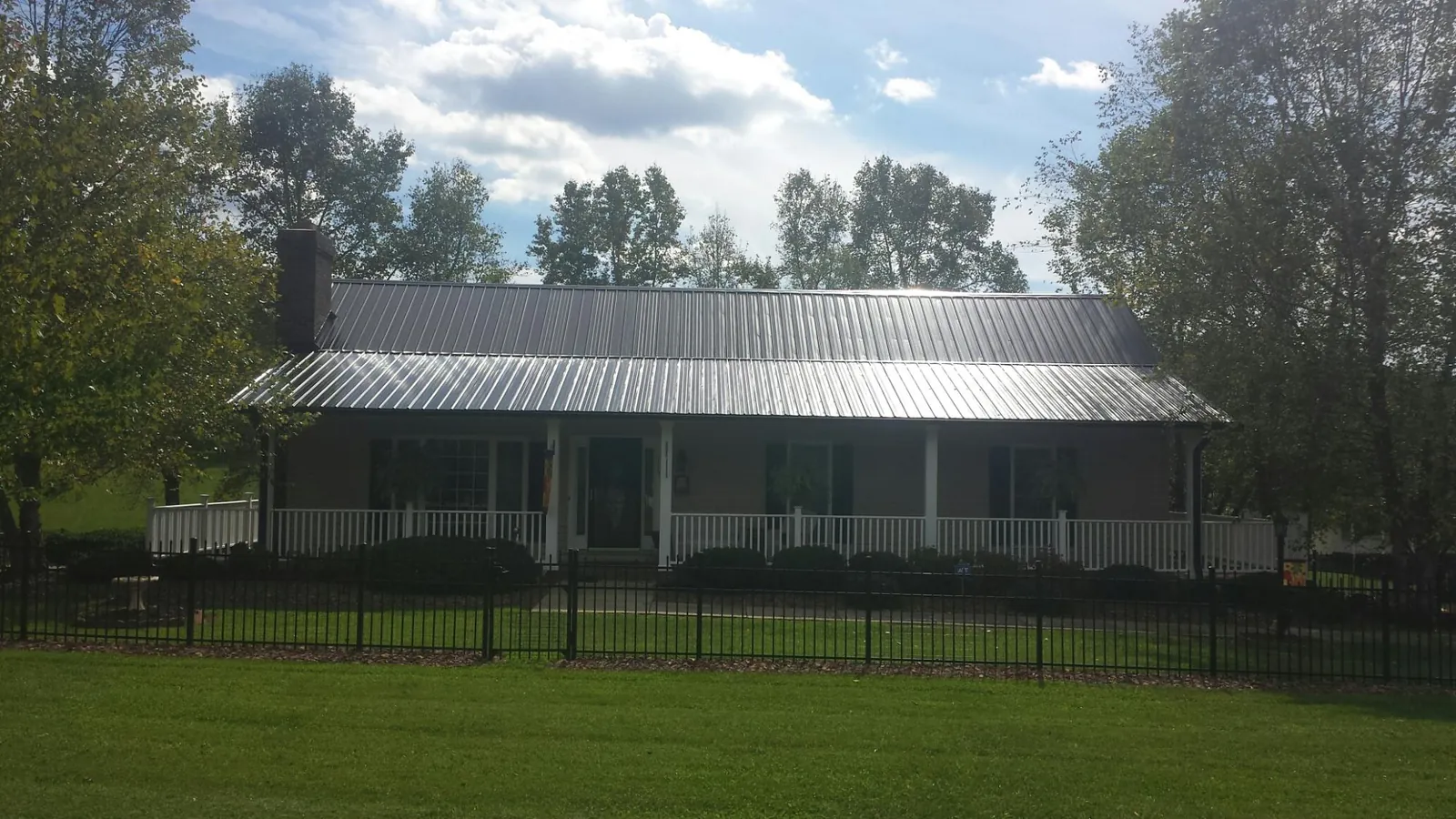 Gray metal roof on a brick ranch with a full width front porch — Gutter Guard Installation work by our crew in Shaniko