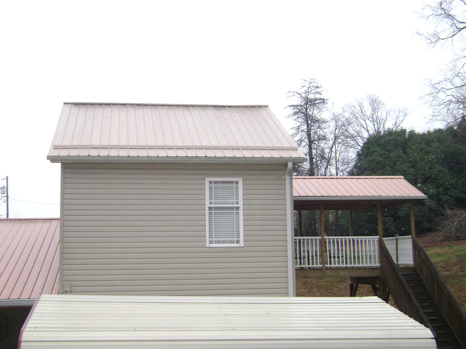 Tan metal roofs on a two story addition and attached porch, from a Roof Replacement job in Shaniko