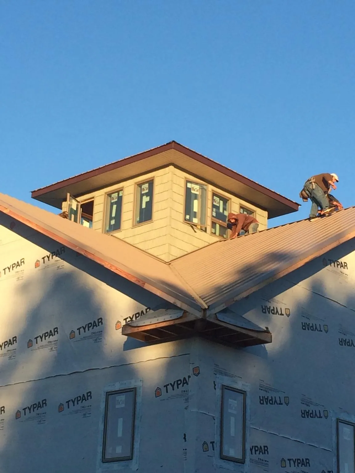 Roofers working around a rooftop cupola on a new metal roof at sunset — Roof Waterproofing in Shaniko by Roofing Brothers
